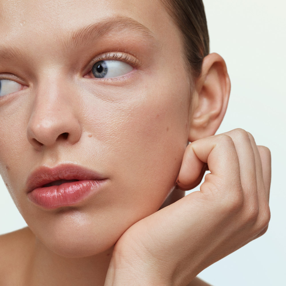 Szklana buteleczka serum z witaminą C na marmurowym blacie w porannym świetle